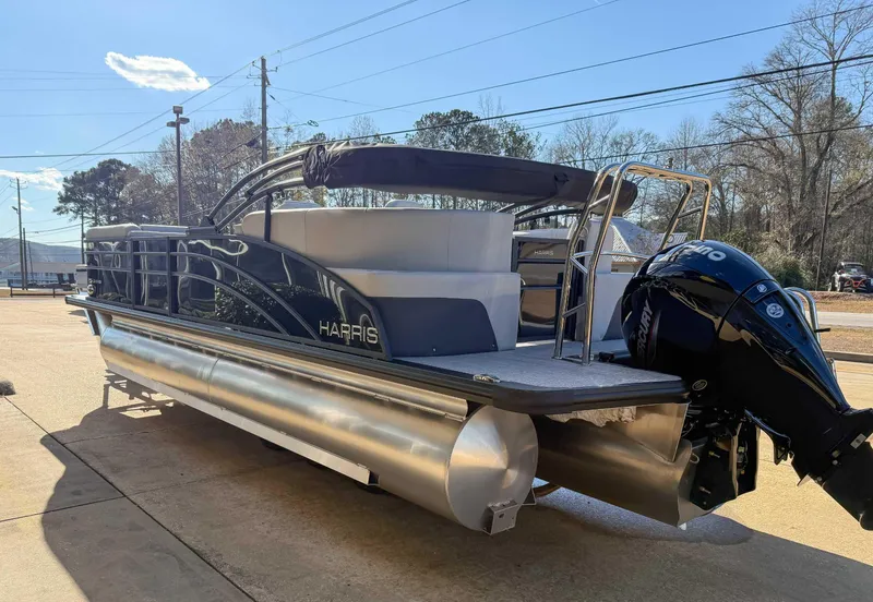 Slide: The Image of 2025 Harris Cruiser 230 CWDH pontoon boat with Mercury outboard engine, parked outdoors. - 6