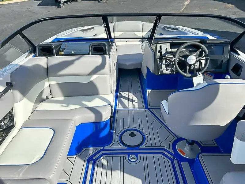 Slide: The Image of 2024 Moomba Mojo boat interior with gray and blue seating, steering wheel, and dashboard. - 13