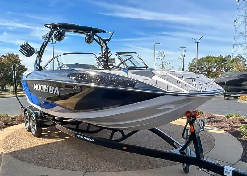 Slide: The Image of 2024 Moomba Mojo boat on trailer, sleek design, parked outdoors under clear sky. - 5