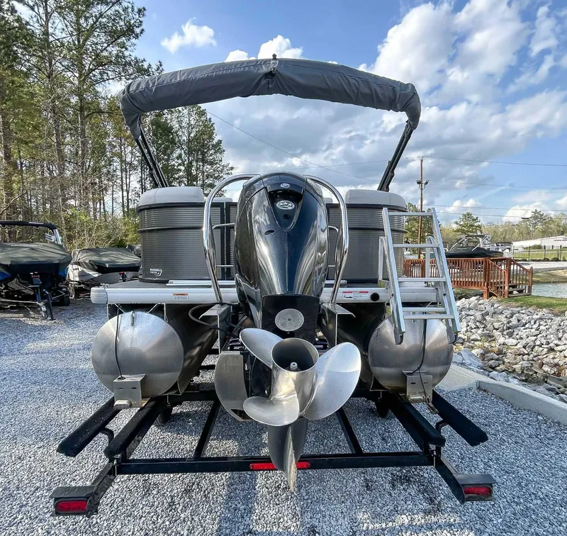 Slide: The Image of 2022 Godfrey Sweetwater pontoon boat with outboard motor on a trailer, under a blue sky. - 6