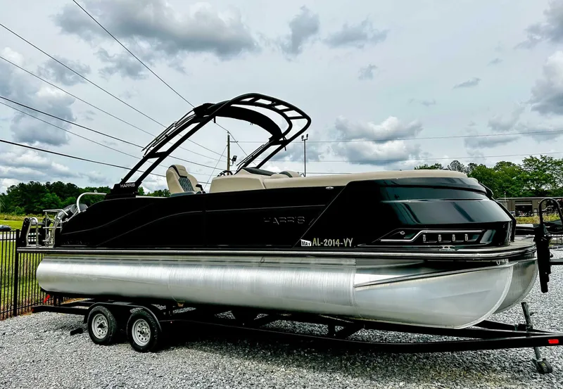 Slide: The Image of 2023 Harris Grand Mariner 230 pontoon boat on trailer, parked outdoors under cloudy sky. - 3