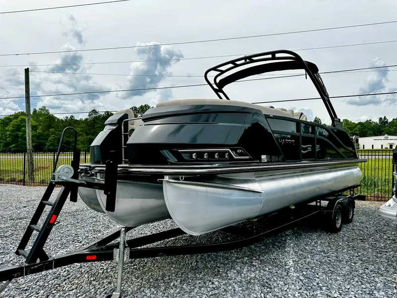 Slide: The Image of 2023 Harris Grand Mariner 230 pontoon boat on trailer, parked on gravel lot. - 6