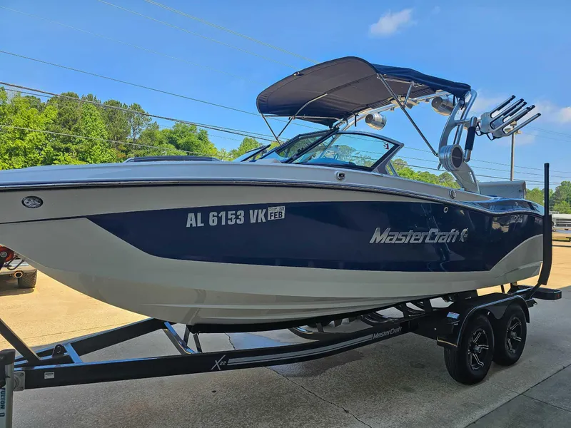 Slide: The Image of 2021 MasterCraft X22 boat on trailer, blue and white, parked outdoors. - 5