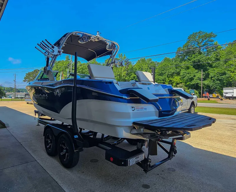 Slide: The Image of 2021 MasterCraft X22 boat on trailer, parked outdoors under clear blue sky. - 7