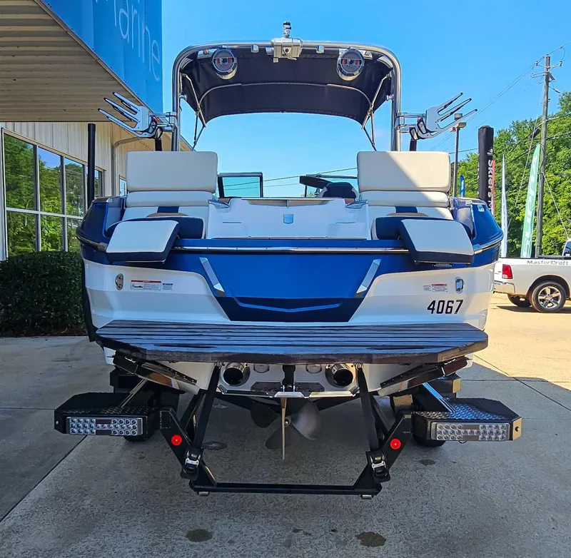 Slide: The Image of 2021 MasterCraft X22 boat, rear view, parked outdoors on a sunny day. - 8