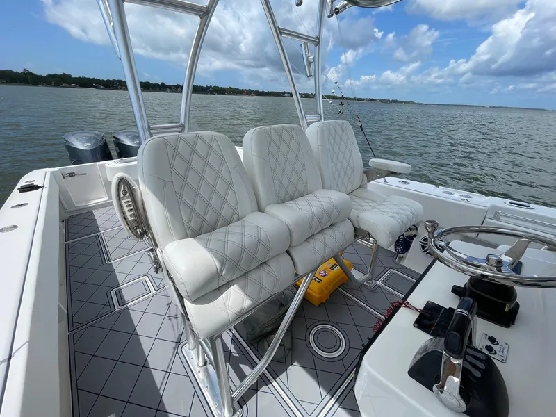 Slide: The Image of 2009 Contender 39 Tournament boat interior with white seating and steering wheel, on calm waters. - 11