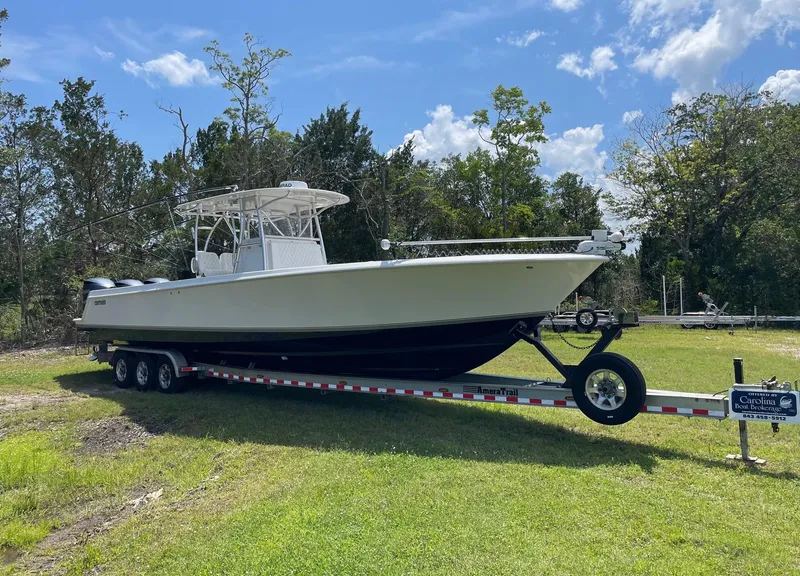 Slide: The Image of 2009 Contender 39 Tournament boat on trailer, parked on grass under blue sky. - 2