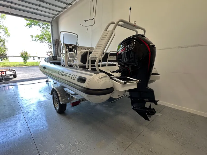 Slide: The Image of 2025 Highfield Sport 560 boat in garage, featuring a powerful outboard motor. - 12