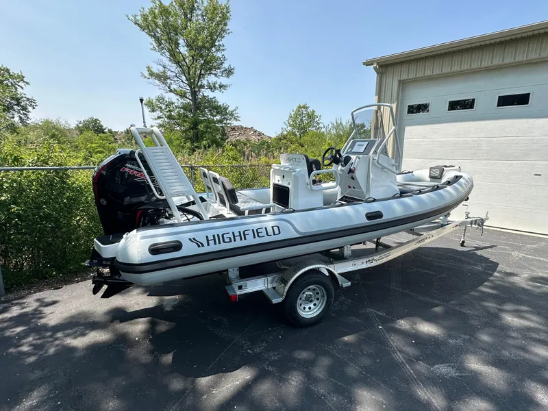Slide: The Image of 2025 Highfield Sport 560 boat on trailer, parked outdoors near a garage. - 3