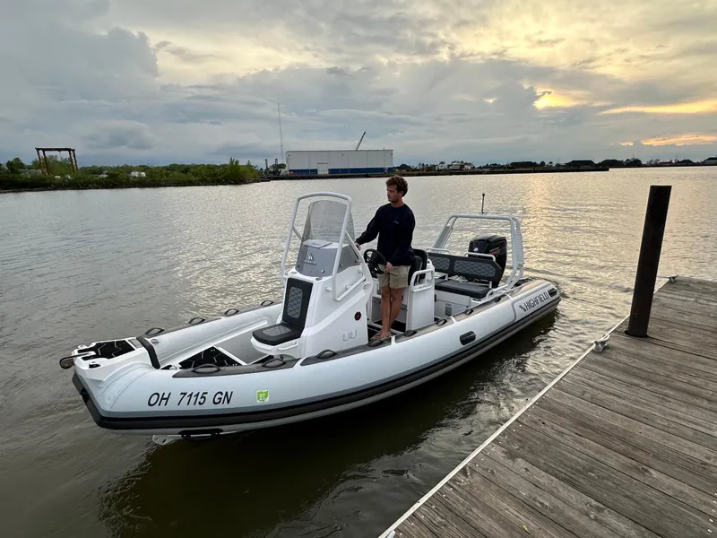 Slide: The Image of 2025 Highfield Sport 560 boat docked at sunset with a person standing at the helm. - 5