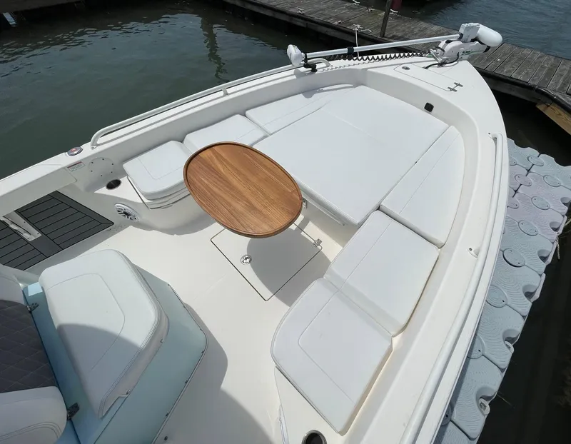 Slide: The Image of 2022 Pathfinder 2600 TRS boat with spacious seating and wooden table, docked by the water. - 24