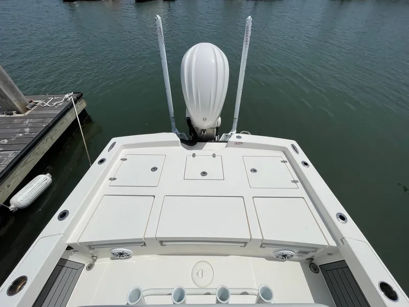 Slide: The Image of 2022 Pathfinder 2600 TRS boat stern view with storage compartments and motor, docked on water. - 25