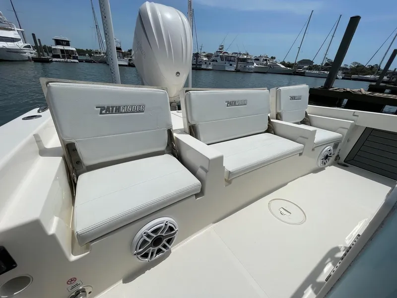 Slide: The Image of 2022 Pathfinder 2600 TRS boat interior with white seating and marina background. - 27