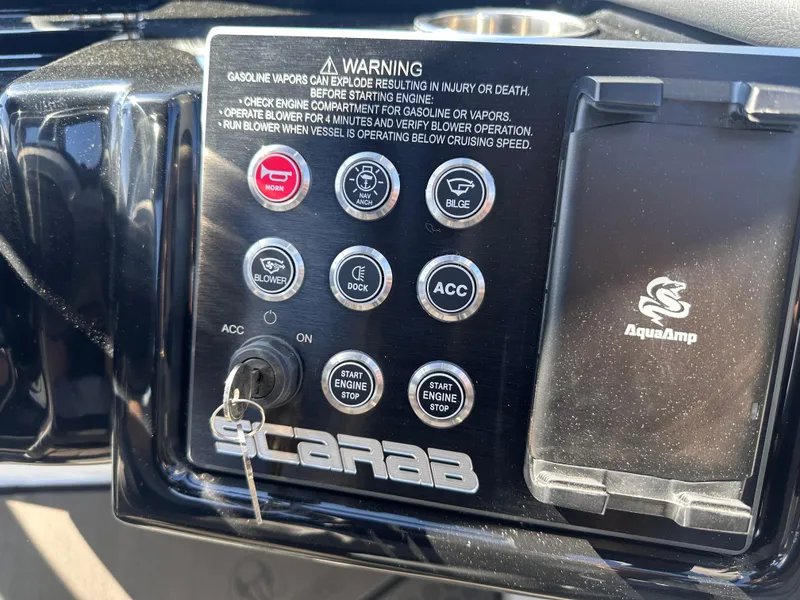 Slide: The Image of Control panel of 2025 Scarab 235 LX boat with warning labels and ignition key. - 13