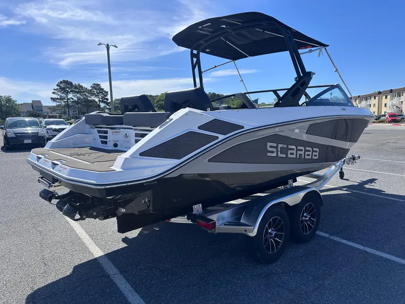 Slide: The Image of 2025 Scarab 235 LX boat on trailer in parking lot, sunny day. - 2
