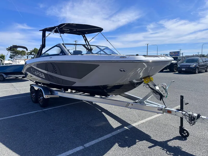 Slide: The Image of 2025 Scarab 235 LX boat on trailer in parking lot under clear blue sky. - 4