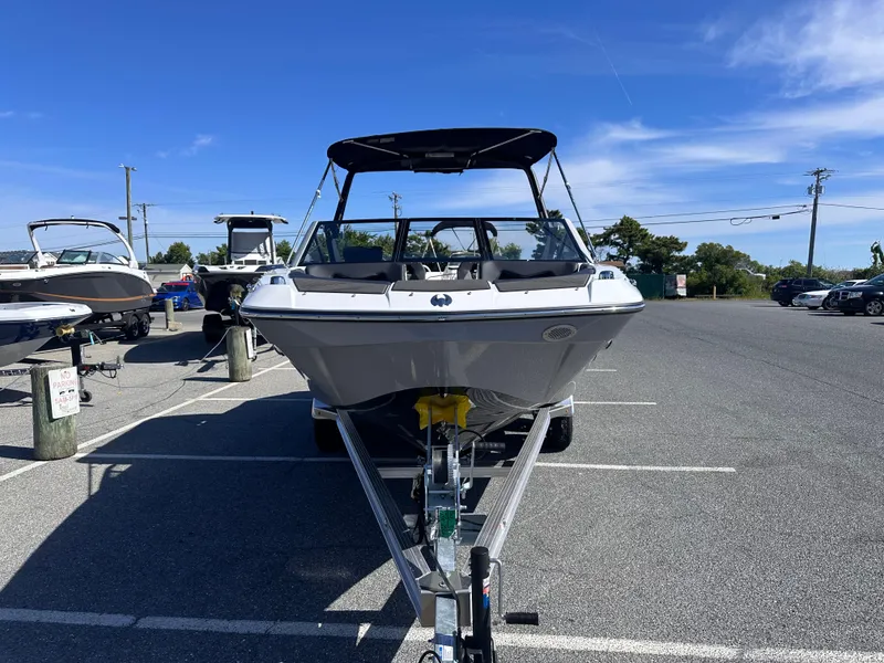 Slide: The Image of 2025 Scarab 235 LX boat on trailer in parking lot under clear blue sky. - 5