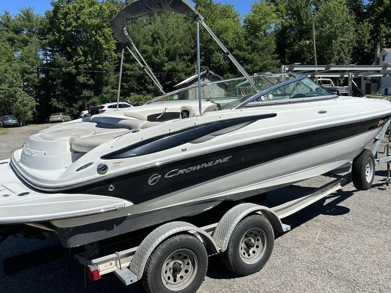 Slide: The Image of 2011 Crownline 220LS boat on trailer, parked outdoors, surrounded by trees. - 15