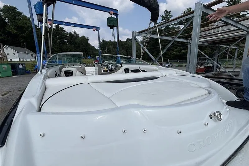 Slide: The Image of 2011 Crownline 220LS boat with white seating, parked outdoors near storage racks. - 24