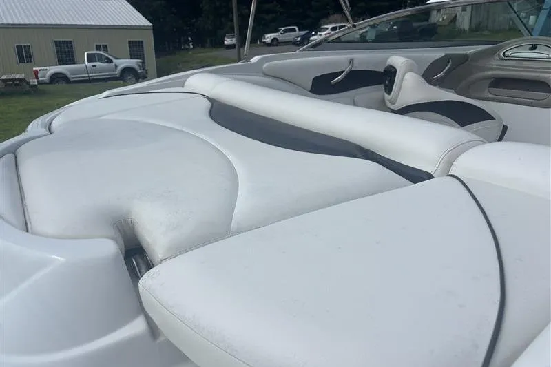 Slide: The Image of 2011 Crownline 220LS boat interior with white and gray seating, parked outdoors. - 26