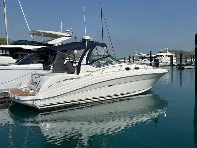 The Image of 2003 Sea Ray 340 Sundancer yacht docked in a marina, reflecting on calm water. - 0