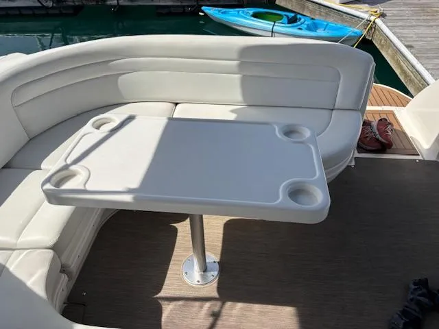 Slide: The Image of 2003 Sea Ray 340 Sundancer cockpit with white seating and table, docked near a kayak. - 10