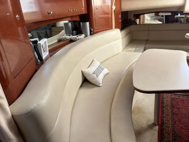 Slide: The Image of 2003 Sea Ray 340 Sundancer interior with curved beige seating and wooden cabinetry. - 3