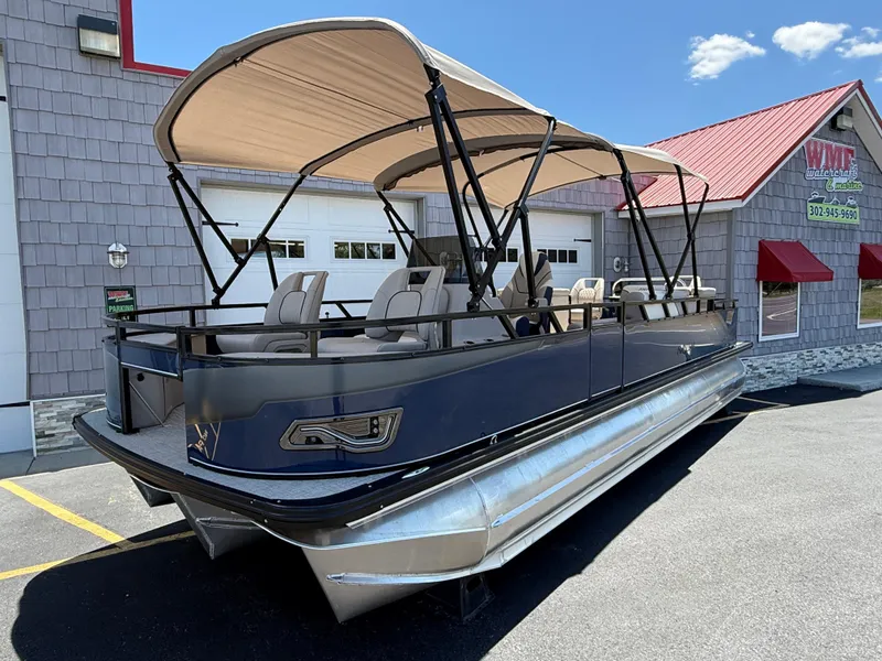 Slide: The Image of 2025 Avalon 2585 Venture 85 Tri Toon boat with center console, parked outdoors. - 2