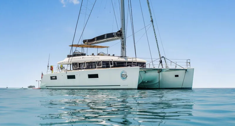The Image of 2020 Lagoon 620 catamaran sailing on calm blue waters under a clear sky. - 1