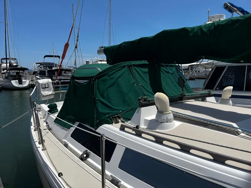 Slide: The Image of 1987 Catalina 34 sailboat docked at marina with green covers. - 10
