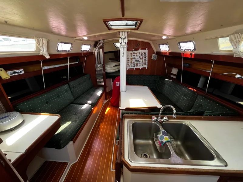 Slide: The Image of Interior of a 1987 Catalina 34 sailboat with cozy seating and a compact kitchen area. - 16