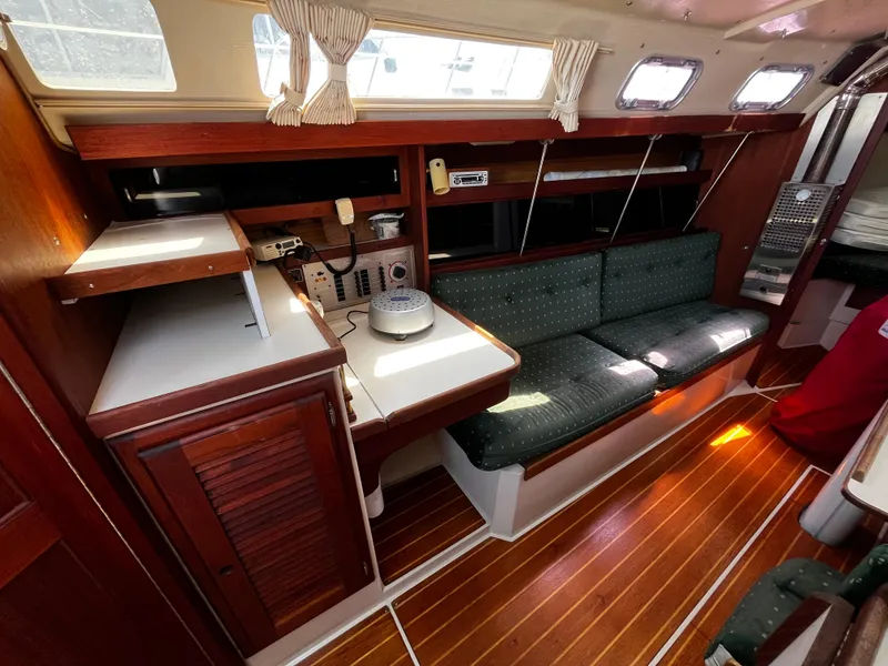 Slide: The Image of 1987 Catalina 34 yacht interior with wood finish, green seating, and natural light. - 18