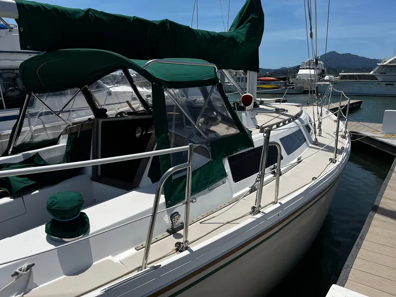 Slide: The Image of 1987 Catalina 34 sailboat docked at marina with green covers and clear skies. - 2