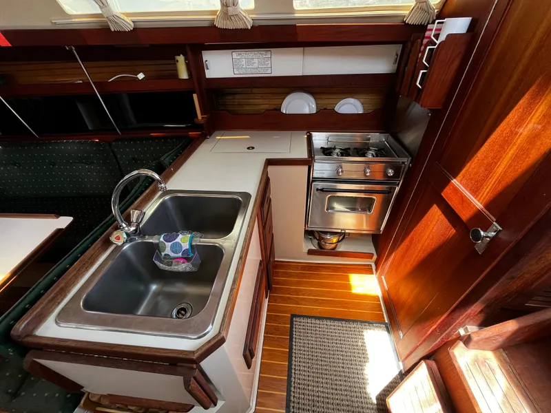 Slide: The Image of 1987 Catalina 34 yacht kitchen with sink, stove, and wooden cabinetry. - 23