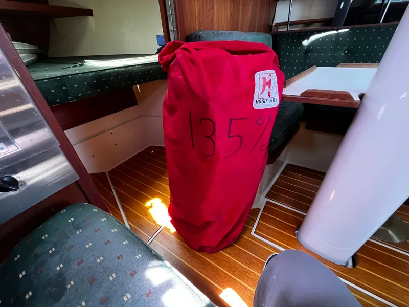 Slide: The Image of Interior of a 1987 Catalina 34 sailboat with a red sail bag marked "135%". - 26