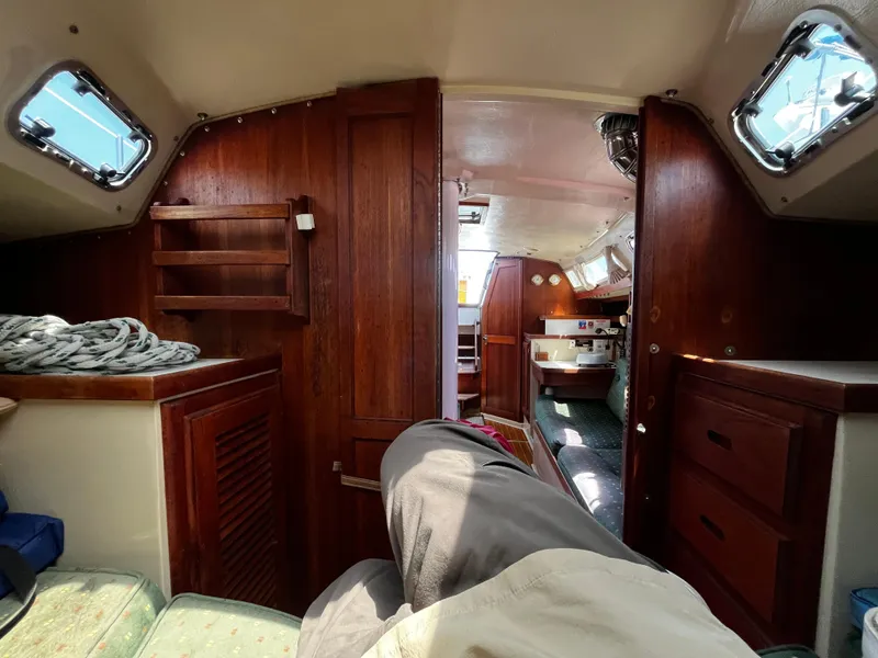 Slide: The Image of Interior of a 1987 Catalina 34 sailboat, featuring wooden cabinetry and cozy seating. - 27