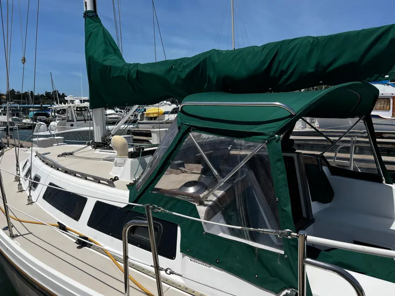 Slide: The Image of 1987 Catalina 34 sailboat docked with green canvas cover and clear windows. - 7