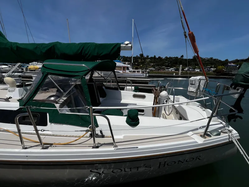 Slide: The Image of 1987 Catalina 34 sailboat docked, featuring green covers and named "Scout's Honor." - 8