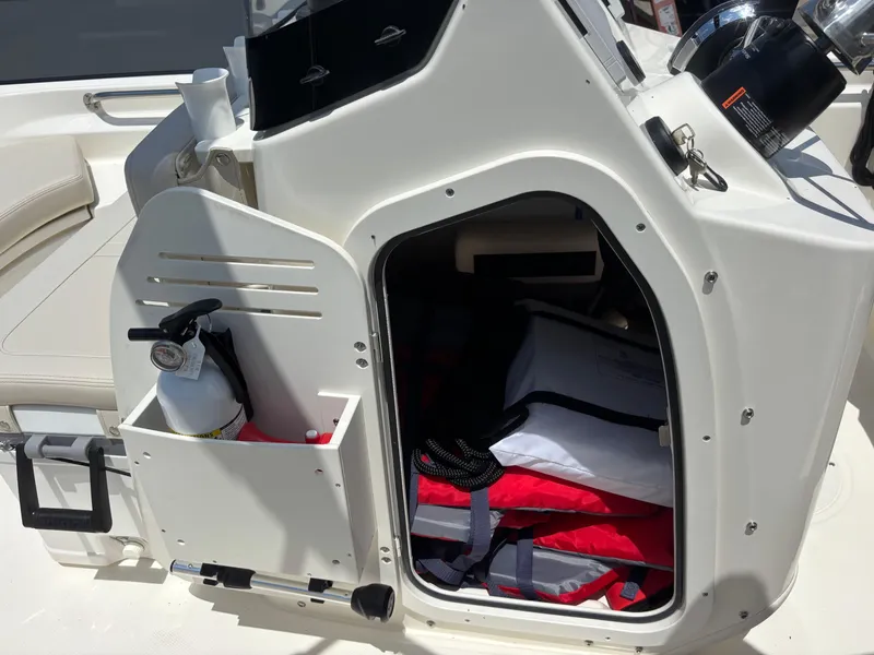 Slide: The Image of 2024 Boston Whaler 170 Montauk storage compartment with safety equipment and life jackets. - 17