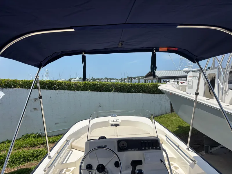 Slide: The Image of 2024 Boston Whaler 170 Montauk boat interior with canopy, docked outdoors. - 18