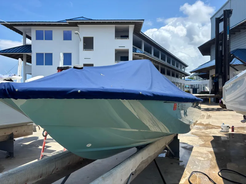 Slide: The Image of 2024 Boston Whaler 170 Montauk boat with blue cover, docked near modern buildings. - 4