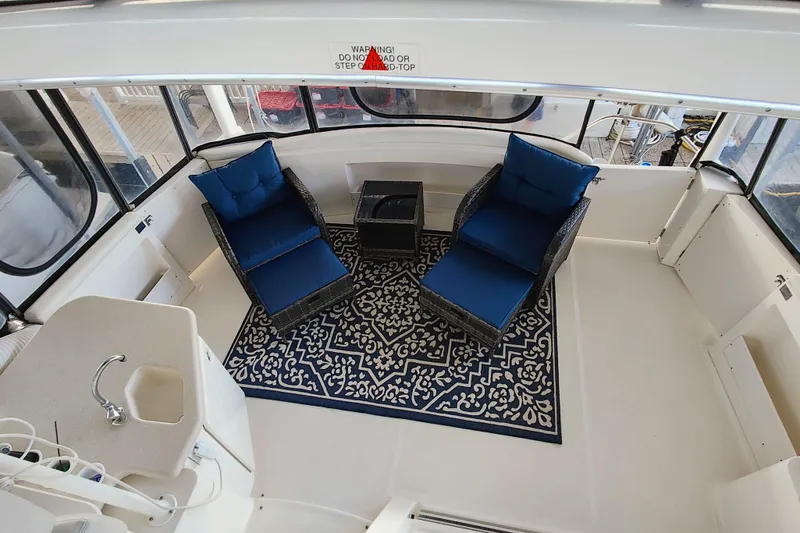 Slide: The Image of 2002 Silverton 43 Motor Yacht interior with blue cushioned chairs and patterned rug. - 15