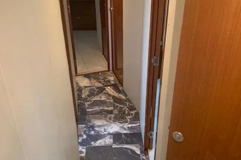 Slide: The Image of Narrow hallway with marble flooring inside a 2002 Viking 55 Convertible yacht. - 12