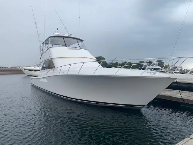 Slide: The Image of 2002 Viking 55 Convertible yacht docked in a marina under cloudy skies. - 16