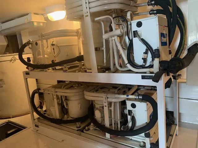 Slide: The Image of Engine room of 2002 Viking 55 Convertible yacht, showcasing complex machinery and piping. - 23