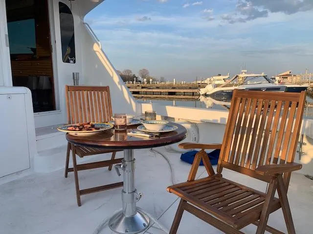 Slide: The Image of Deck of 2002 Viking 55 Convertible yacht with wooden chairs and table, marina view. - 4