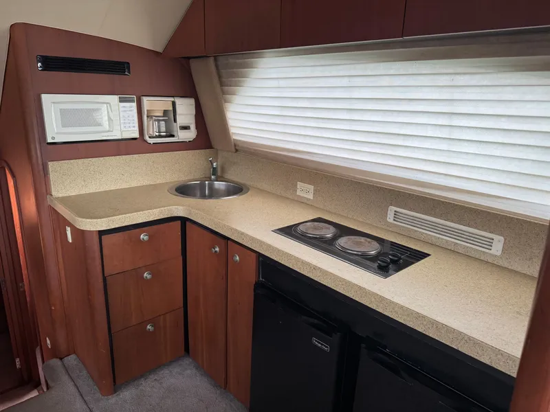 Slide: The Image of 2004 Luhrs 36 Convertible yacht kitchen with sink, stove, microwave, and storage cabinets. - 16
