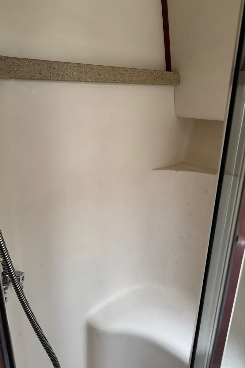 Slide: The Image of 2004 Luhrs 36 Convertible boat shower interior with white walls and chrome fixtures. - 21