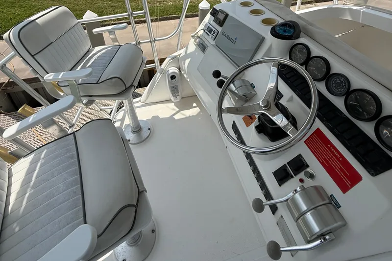 Slide: The Image of 2004 Luhrs 36 Convertible boat helm with steering wheel, gauges, and captain's chairs. - 9