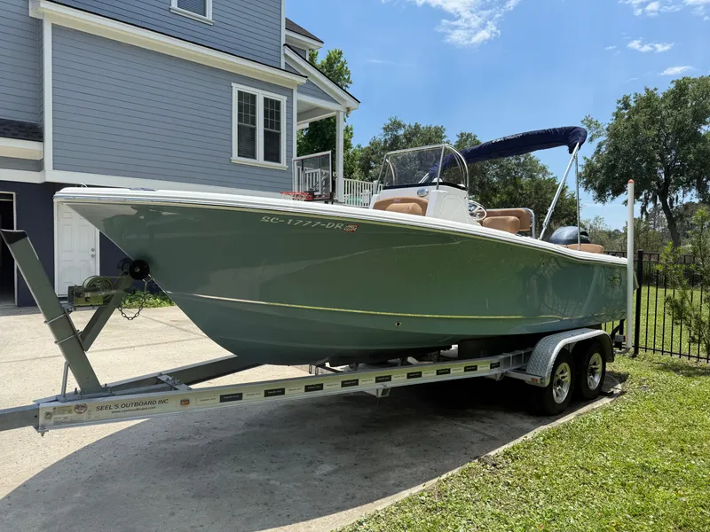 Slide: The Image of 2021 Sea Hunt Ultra 219 boat on trailer, parked near a house on a sunny day. - 3